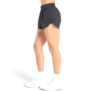 Side view of woman wearing black lightweight training shorts and white sneakers.