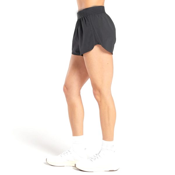 Side view of woman wearing black lightweight training shorts and white sneakers.