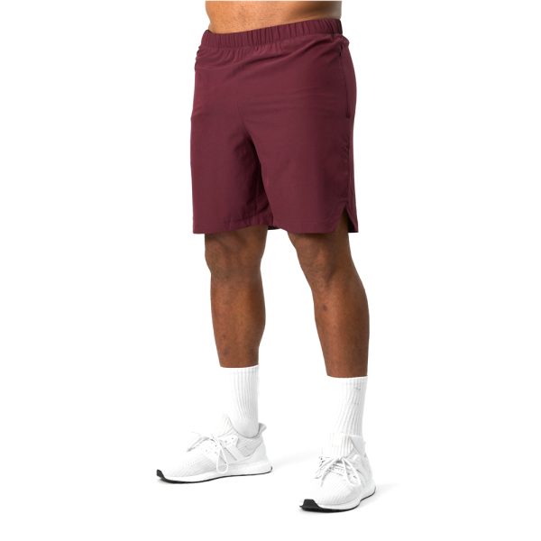 Man wearing maroon training shorts with elastic waistband and white sneakers.