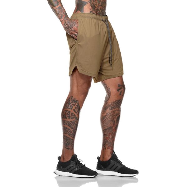 Tattooed male model wearing khaki gym shorts with drawstring and side slit.